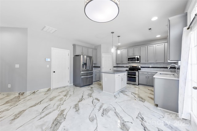 kitchen featuring stainless steel appliances, gray cabinetry, hanging light fixtures, a kitchen island, and sink