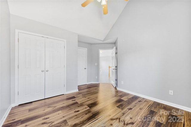 unfurnished bedroom with vaulted ceiling, ceiling fan, a closet, and wood-type flooring