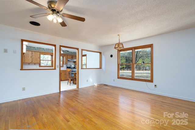 empty room featuring light wood-type flooring, ceiling fan, a textured ceiling, and plenty of natural light