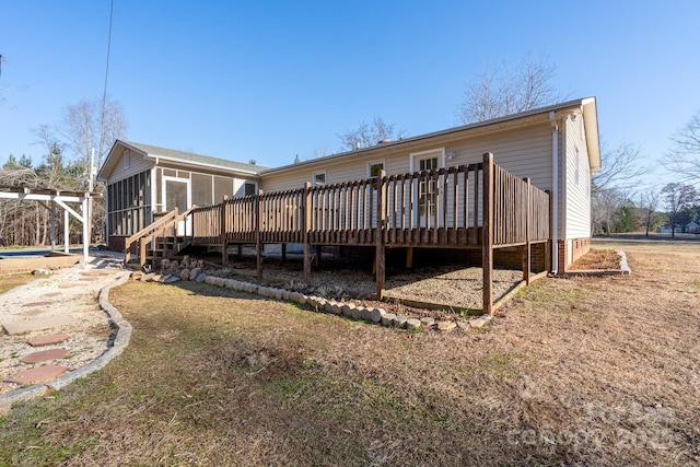 rear view of house with a yard, a wooden deck, and a sunroom