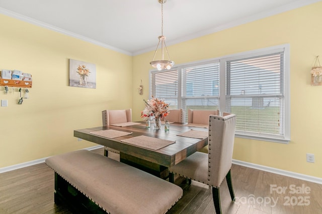 dining space featuring baseboards, wood finished floors, and crown molding