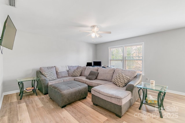 living area featuring baseboards, a ceiling fan, visible vents, and light wood-style floors