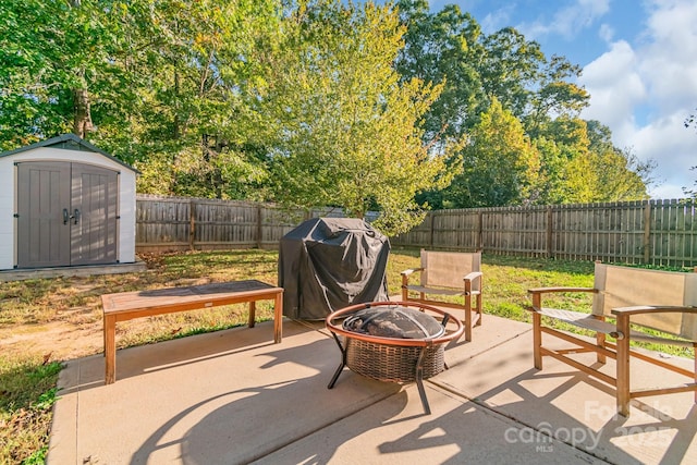 view of patio with an outbuilding, an outdoor fire pit, a fenced backyard, a storage shed, and a grill