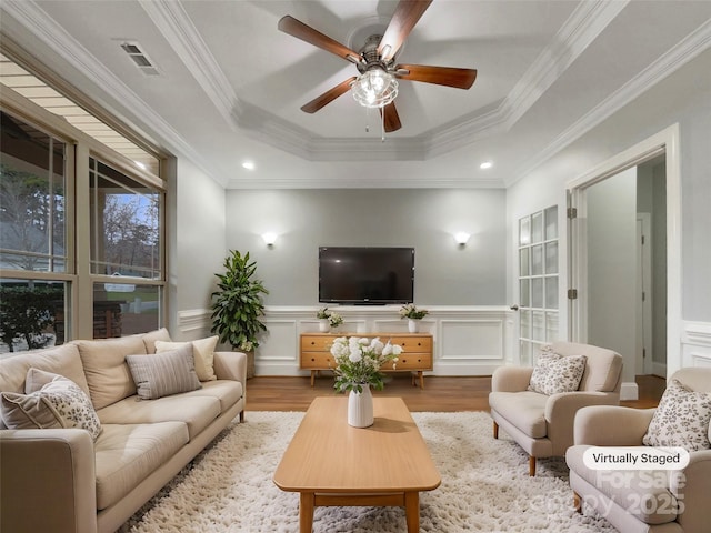 living room featuring ornamental molding, ceiling fan, light hardwood / wood-style floors, and a raised ceiling