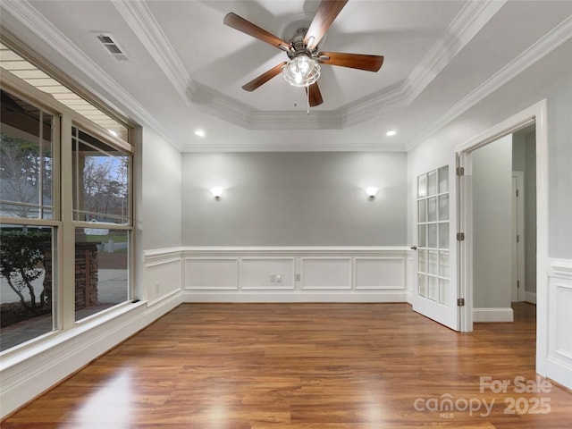 unfurnished room with ceiling fan, crown molding, a raised ceiling, and wood-type flooring