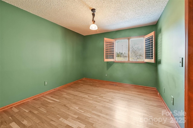 spare room featuring a textured ceiling and light wood-type flooring