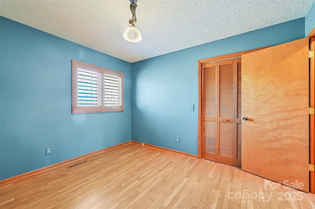 unfurnished bedroom featuring a textured ceiling, a closet, and light wood-type flooring