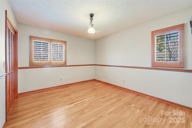 spare room with light hardwood / wood-style floors and a textured ceiling