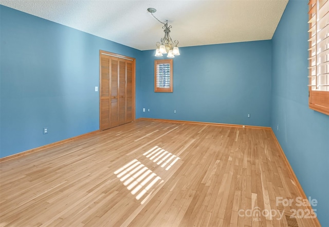 unfurnished room with light hardwood / wood-style flooring and a chandelier