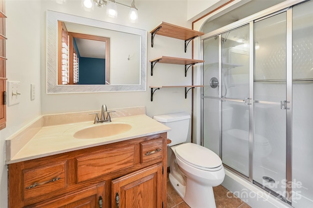 bathroom with vanity, a shower with shower door, tile patterned floors, and toilet