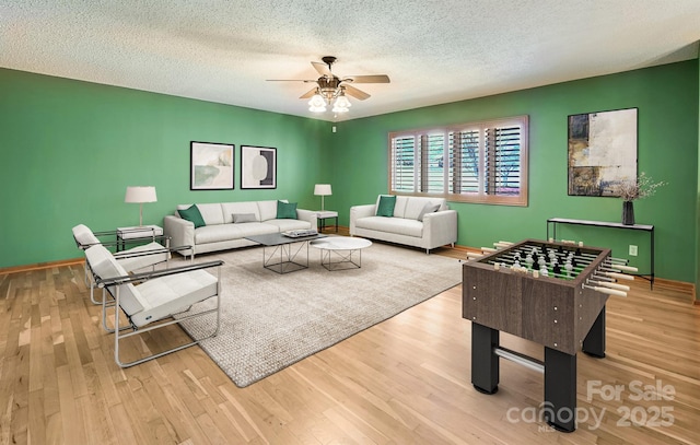 living room with ceiling fan, a textured ceiling, and light wood-type flooring