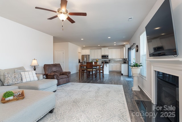 living room with ceiling fan and dark wood-type flooring