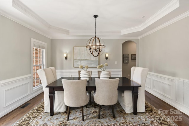 dining room with dark hardwood / wood-style flooring, a raised ceiling, a chandelier, and crown molding