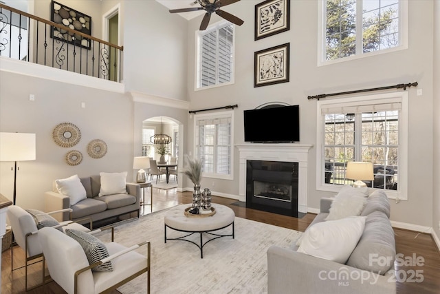 living room featuring a high ceiling, ceiling fan, and hardwood / wood-style flooring