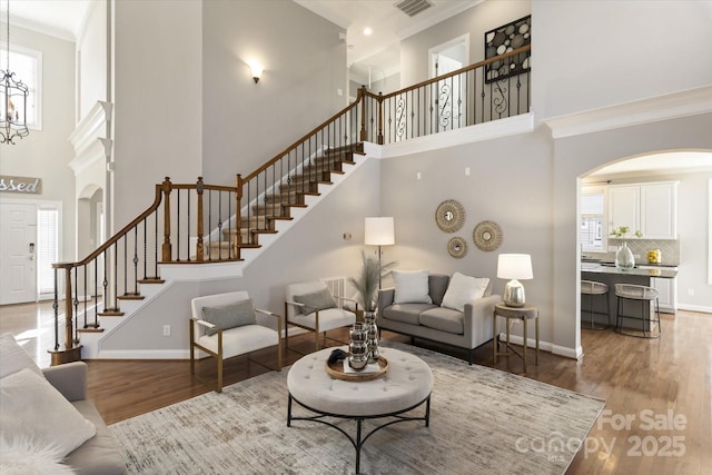 living room featuring a high ceiling, wood-type flooring, and ornamental molding