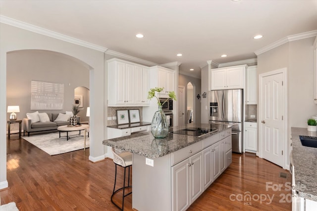 kitchen featuring a center island, stainless steel appliances, decorative backsplash, crown molding, and white cabinets