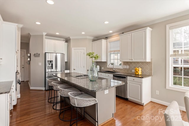 kitchen featuring stainless steel appliances, a kitchen island, white cabinetry, dark stone countertops, and sink