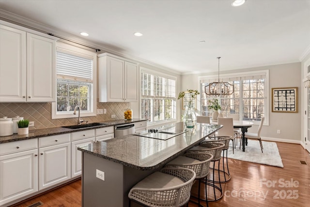 kitchen featuring sink, decorative light fixtures, white cabinetry, dishwasher, and a kitchen island