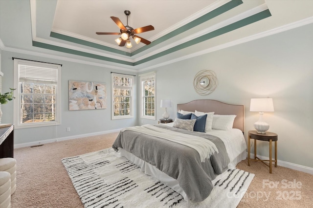 carpeted bedroom with ceiling fan, ornamental molding, and a tray ceiling