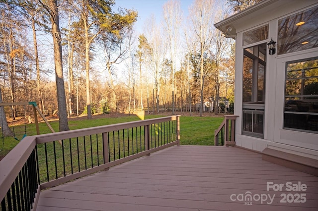 wooden deck featuring a playground, a sunroom, and a lawn