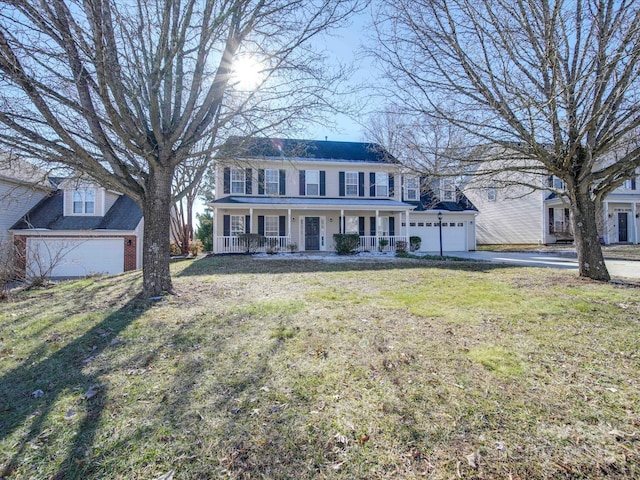 colonial-style house featuring a porch, a garage, and a front yard