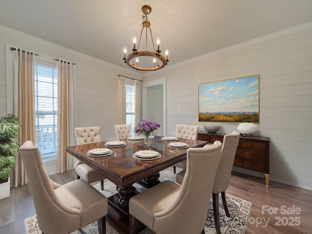 dining room with crown molding, an inviting chandelier, and light hardwood / wood-style floors