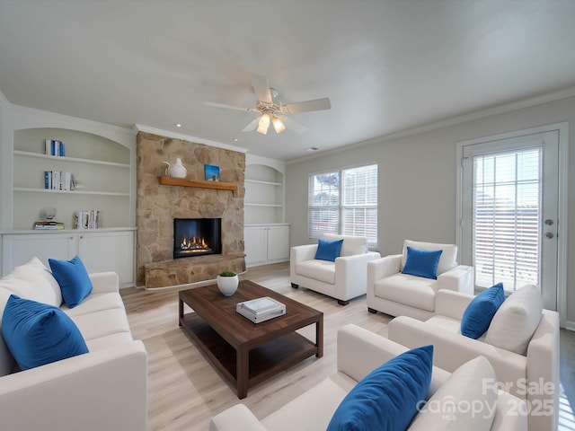 living room featuring crown molding, built in features, and light hardwood / wood-style flooring