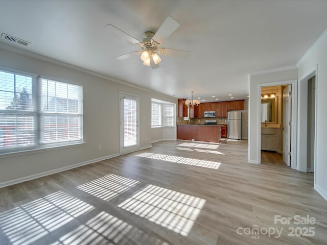 unfurnished living room featuring crown molding, sink, ceiling fan with notable chandelier, and light wood-type flooring