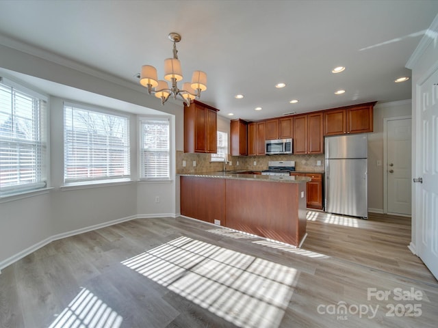 kitchen with hanging light fixtures, stainless steel appliances, light stone countertops, decorative backsplash, and kitchen peninsula