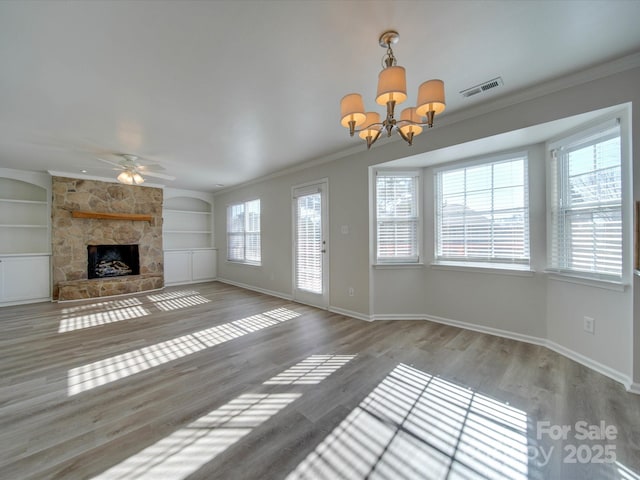 unfurnished living room with hardwood / wood-style flooring, built in features, a fireplace, ornamental molding, and ceiling fan with notable chandelier