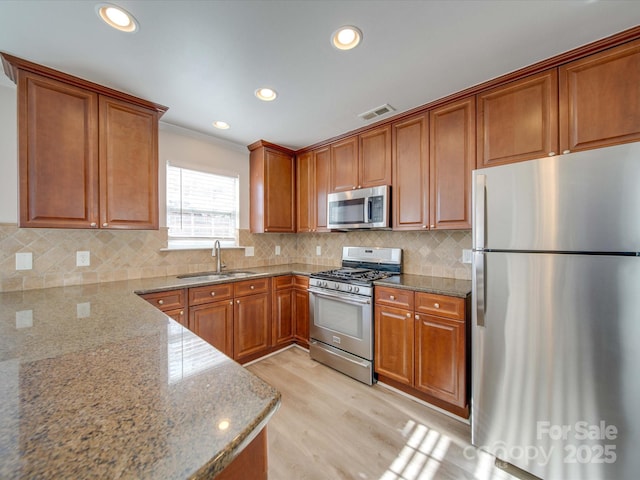 kitchen featuring light stone counters, stainless steel appliances, sink, and decorative backsplash