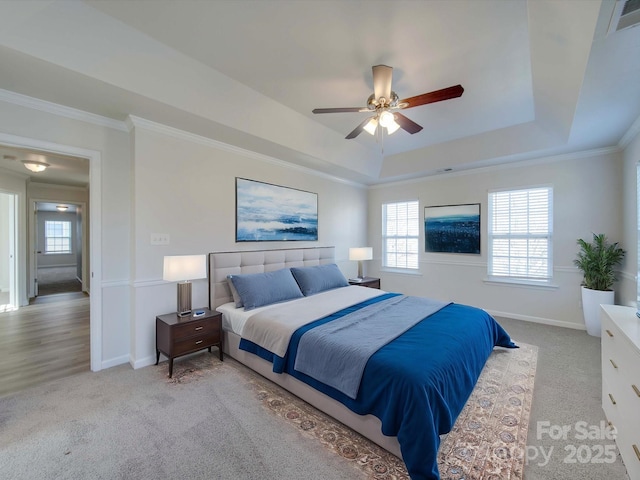 carpeted bedroom with multiple windows, crown molding, a raised ceiling, and ceiling fan