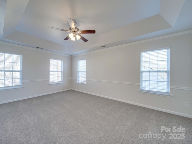 carpeted empty room with crown molding, a tray ceiling, and ceiling fan