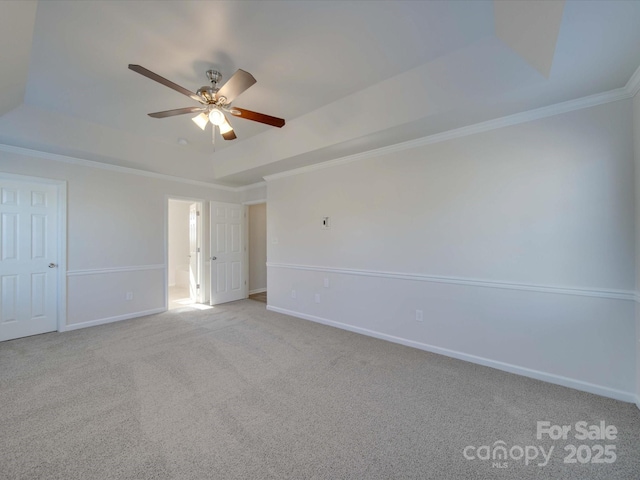 unfurnished room with light colored carpet, ornamental molding, a raised ceiling, and ceiling fan