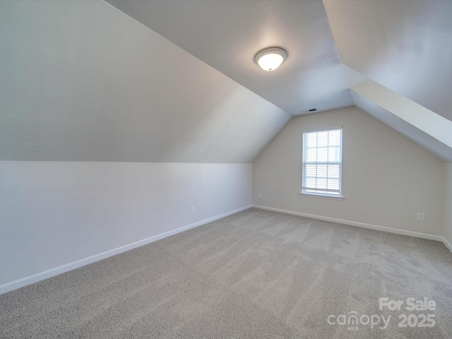 additional living space featuring light carpet and vaulted ceiling