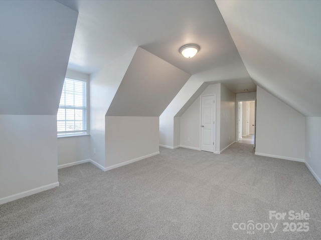 bonus room with lofted ceiling and light carpet