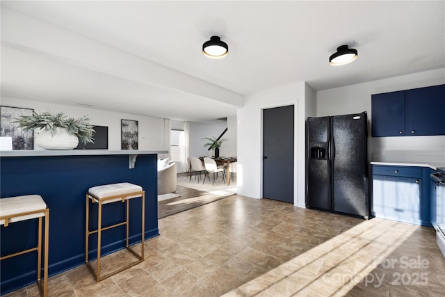 kitchen with blue cabinetry, black refrigerator with ice dispenser, and a kitchen bar