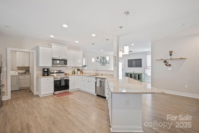 kitchen with white cabinetry, stainless steel appliances, washer / dryer, decorative light fixtures, and kitchen peninsula