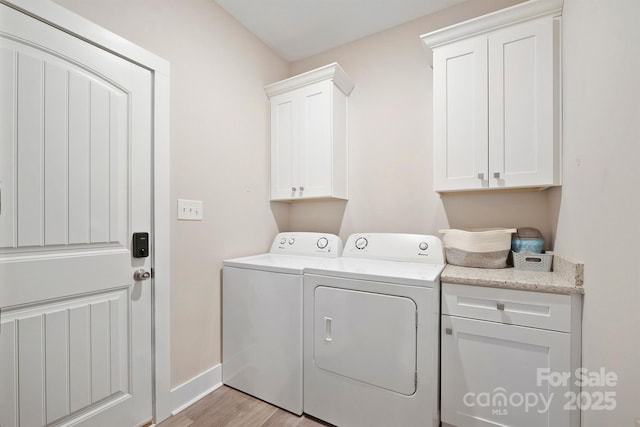 laundry room featuring cabinets, washing machine and dryer, and light hardwood / wood-style flooring