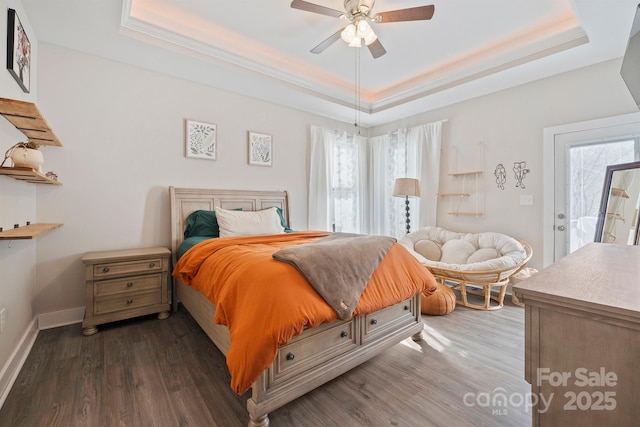 bedroom with ceiling fan, dark hardwood / wood-style flooring, a raised ceiling, and access to outside