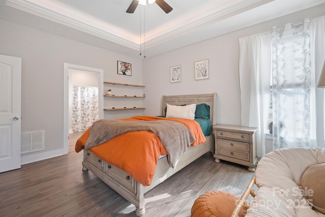 bedroom with multiple windows, dark hardwood / wood-style floors, a raised ceiling, and ceiling fan