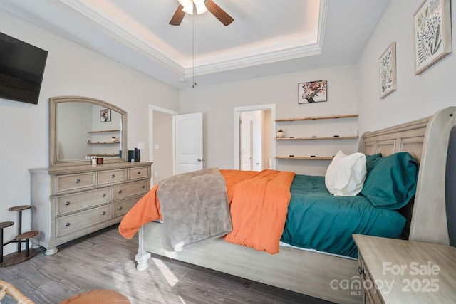 bedroom with crown molding, ceiling fan, a raised ceiling, and hardwood / wood-style floors