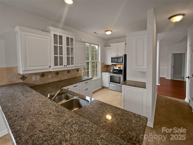 kitchen with sink, stainless steel appliances, white cabinetry, and kitchen peninsula