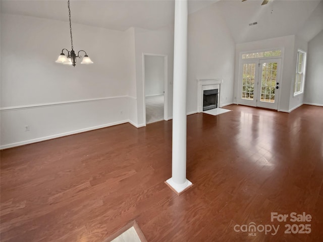 unfurnished living room featuring ceiling fan with notable chandelier, dark wood-type flooring, high vaulted ceiling, and a fireplace