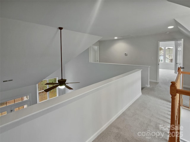 hallway with vaulted ceiling and light colored carpet