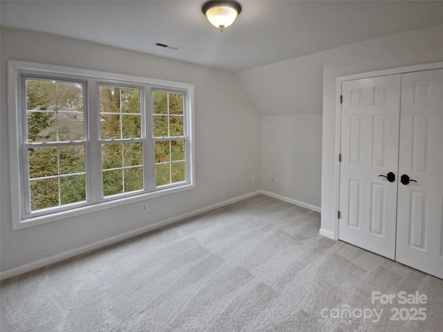 bonus room featuring lofted ceiling, light carpet, and a healthy amount of sunlight