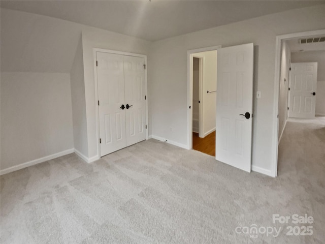 unfurnished bedroom featuring a closet and light colored carpet