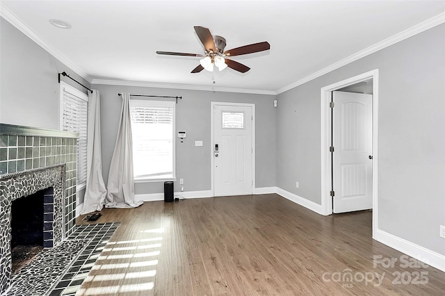 entrance foyer with ceiling fan, dark wood-type flooring, a tile fireplace, and crown molding