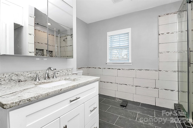 bathroom with walk in shower, vanity, tile walls, and tile patterned floors