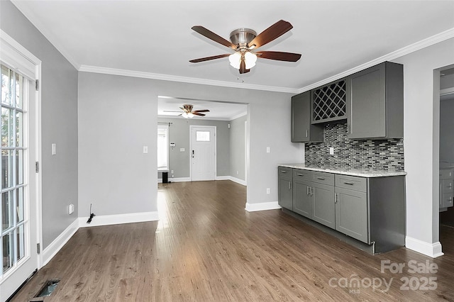 kitchen with wood-type flooring, backsplash, ornamental molding, ceiling fan, and gray cabinetry